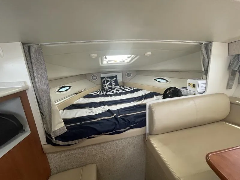 Slide: The Image of 2004 Bayliner 285 cabin interior with striped bedding and nautical decor. - 8