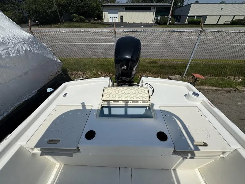 Slide: The Image of 2017 Mako 21 Pro Skiff CC boat with outboard motor, docked near a fence. - 8