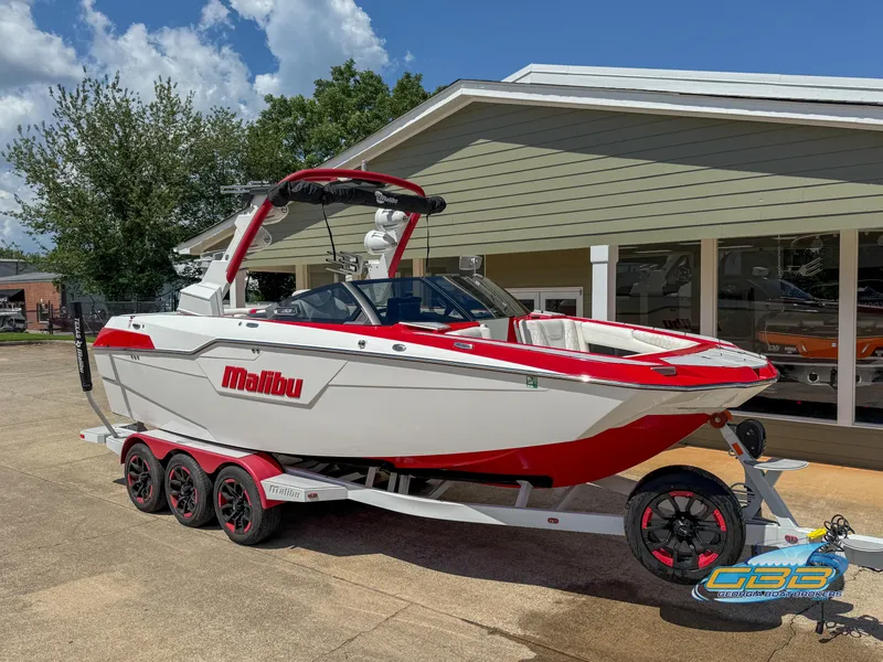 Slide: The Image of 2021 Malibu M240 boat on trailer, red and white design, parked outdoors. - 21