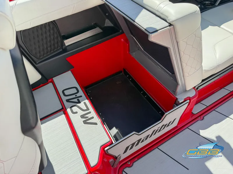 Slide: The Image of 2021 Malibu M240 boat interior with red accents and seating. - 39