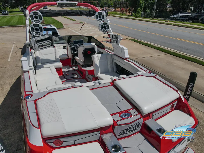 Slide: The Image of 2021 Malibu M240 boat with sleek white and red interior, parked on a sunny street. - 6