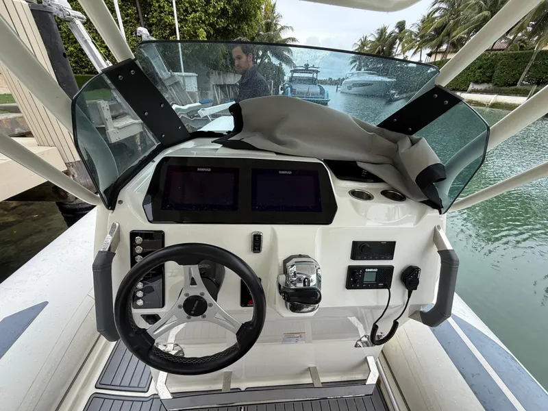 Slide: The Image of Control panel of a 2021 Brig 350 Merc boat, featuring steering wheel and navigation screens. - 22