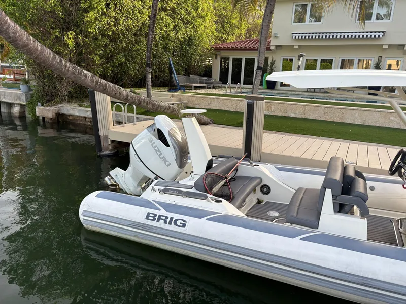 Slide: The Image of 2021 Brig 350 Merc boat docked by a waterfront home with lush greenery. - 25