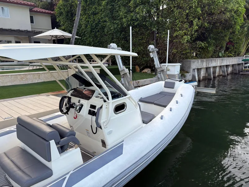 Slide: The Image of 2021 Brig 350 Merc boat docked by a waterfront home with lush greenery. - 5