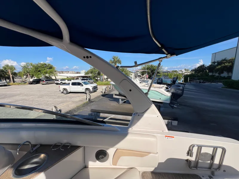 Slide: The Image of 2018 Four Winns HD270 OB boat interior with blue canopy, parked near vehicles and other boats. - 20