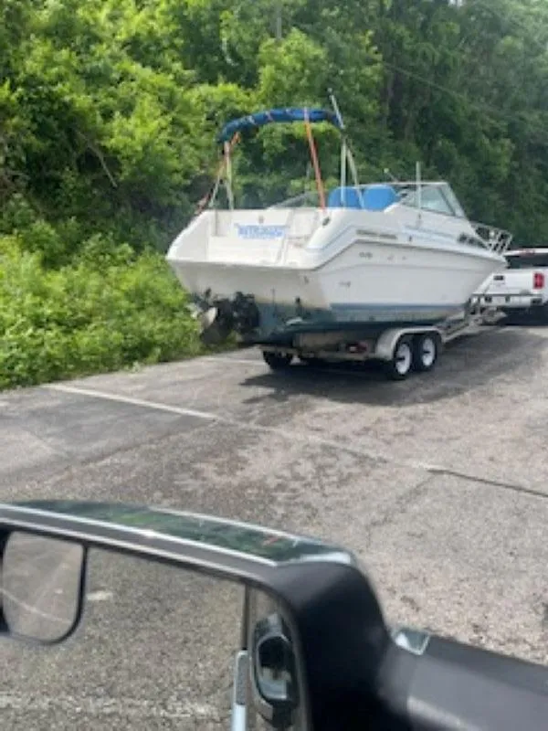 Slide: The Image of 1989 Sea Ray 250 DA boat on trailer, parked near lush greenery. - 4