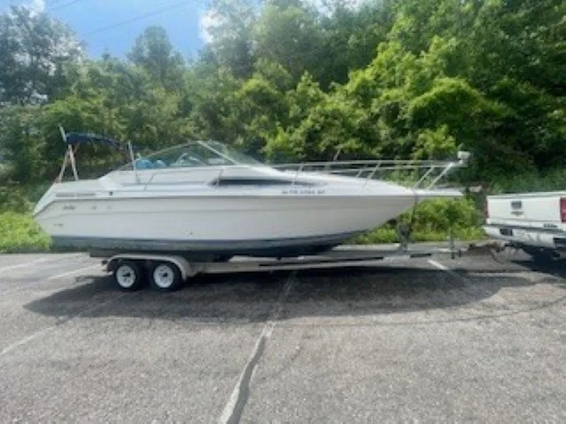 Slide: The Image of 1989 Sea Ray 250 DA boat on trailer, parked outdoors with lush greenery background. - 5