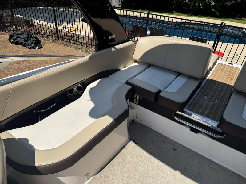 Slide: The Image of 2014 Regal 2300 Bowrider interior with beige seating and wood accents near a pool. - 17