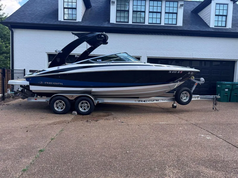 Slide: The Image of 2014 Regal 2300 Bowrider boat on trailer, parked in front of a garage. - 2