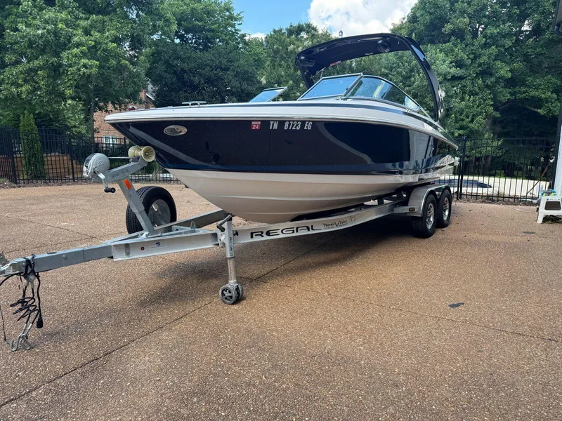 Slide: The Image of 2014 Regal 2300 Bowrider boat on trailer, parked outdoors with trees in background. - 4