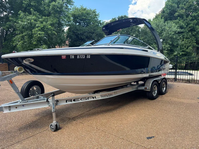 Slide: The Image of 2014 Regal 2300 Bowrider boat on trailer, parked outdoors with trees in background. - 5