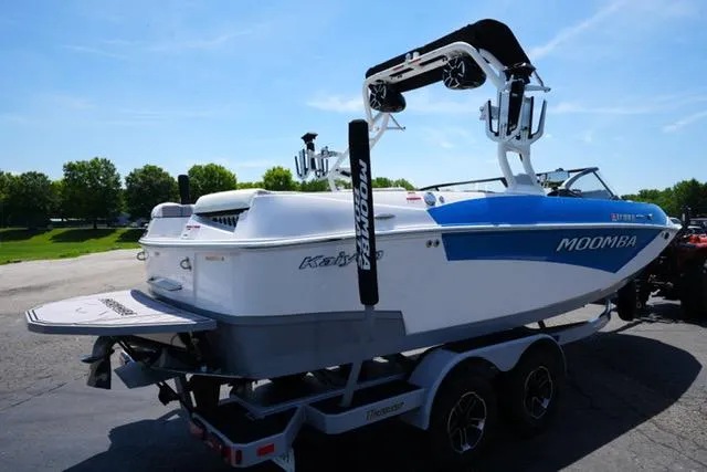 Slide: The Image of 2023 Moomba Kaiyen boat on trailer, blue and white design, parked outdoors. - 3