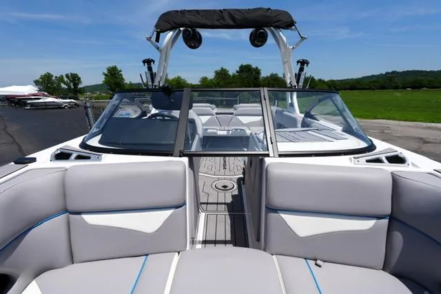 Slide: The Image of 2023 Moomba Kaiyen boat interior with gray seating and open windshield, parked outdoors. - 7