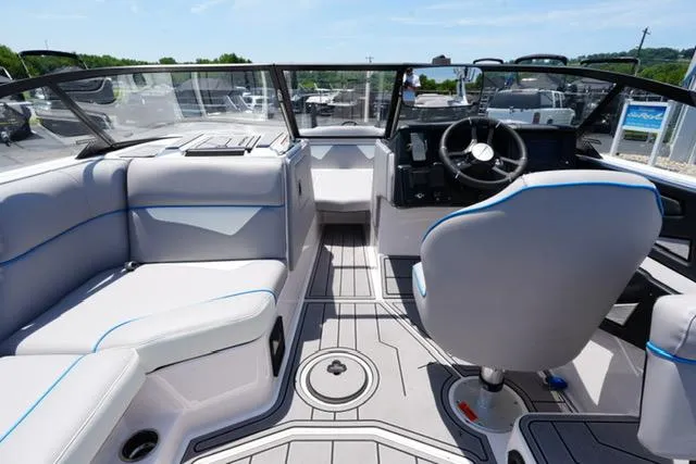 Slide: The Image of 2023 Moomba Kaiyen boat interior with modern seating and steering wheel, under clear blue skies. - 8