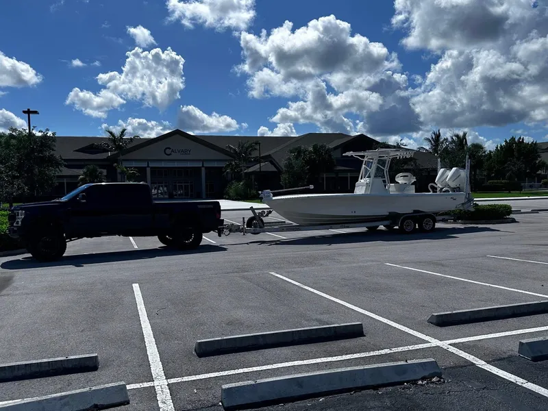 Slide: The Image of 2023 SeaVee 270Z boat on trailer, parked in sunny lot with truck. - 12