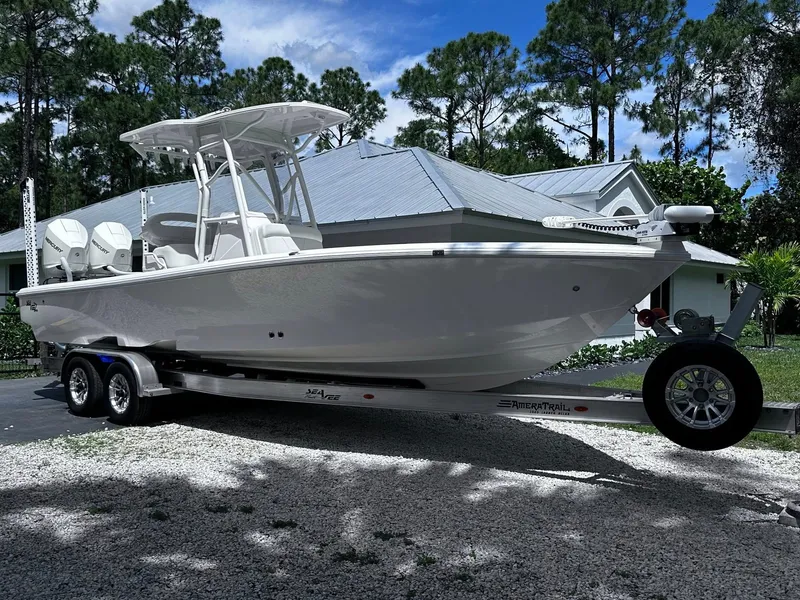 Slide: The Image of 2023 SeaVee 270Z boat on trailer, parked outdoors with trees and house in background. - 18