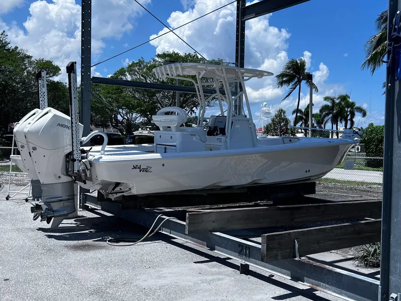Slide: The Image of 2023 SeaVee 270Z boat on lift, sunny day, palm trees in background. - 5