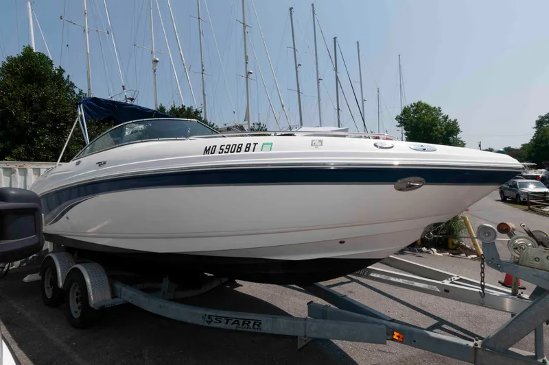 The Image of 2004 Chaparral 230 SSi boat on trailer, parked near marina with sailboats in background. - 0
