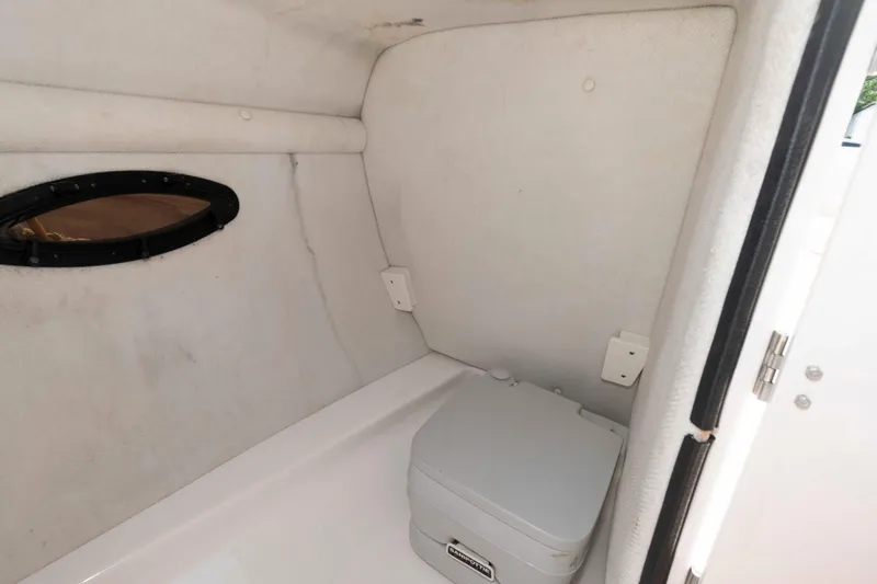 Slide: The Image of 2004 Chaparral 230 SSi boat interior with compact toilet and small window. - 10
