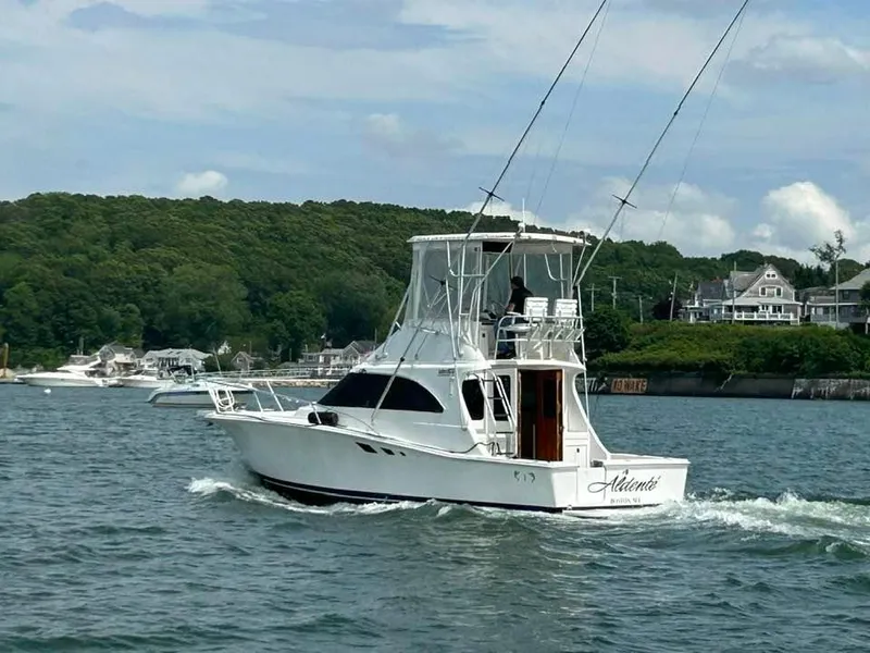 Slide: The Image of 1996 Luhrs 32 Convertible boat cruising on a scenic waterway near lush green shoreline. - 1