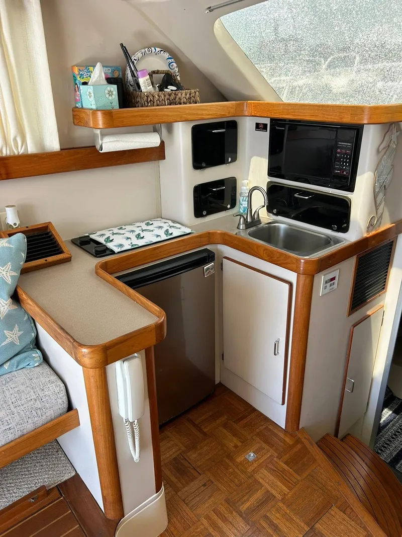 Slide: The Image of Compact kitchen area in a 1996 Luhrs 32 Convertible boat with wood accents and modern appliances. - 18