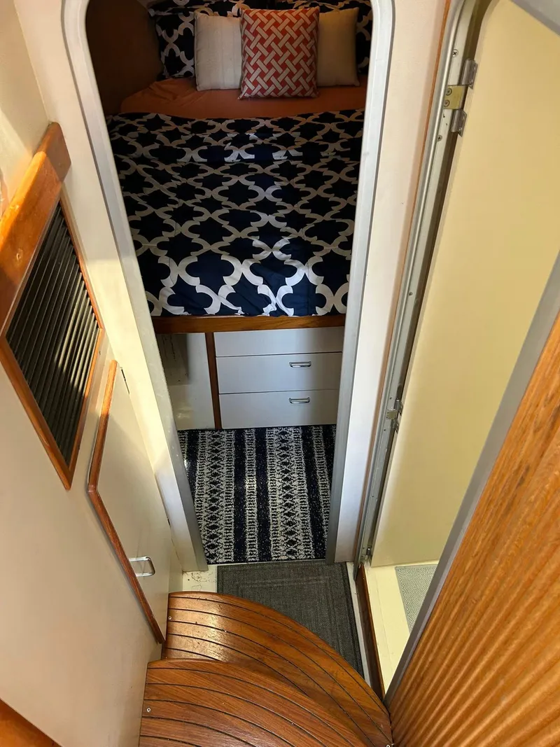 Slide: The Image of 1996 Luhrs 32 Convertible cabin interior with patterned bedding and wooden steps. - 20