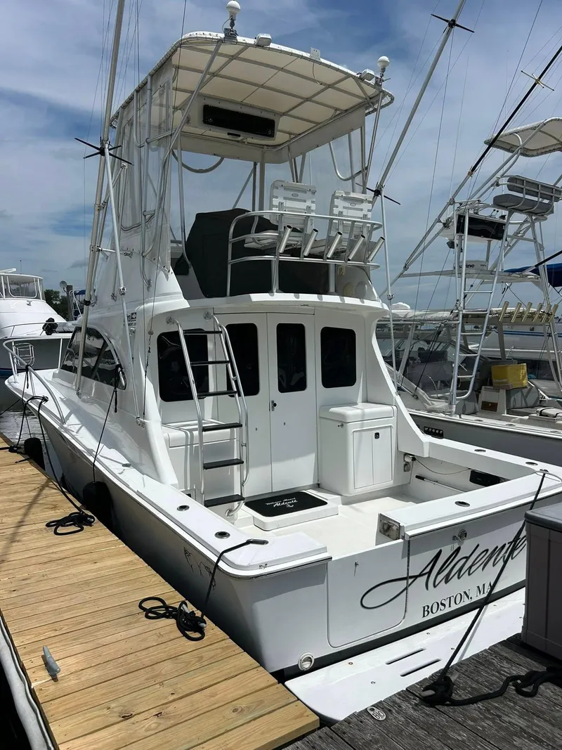 Slide: The Image of 1996 Luhrs 32 Convertible boat docked, featuring a flybridge and spacious deck area. - 4