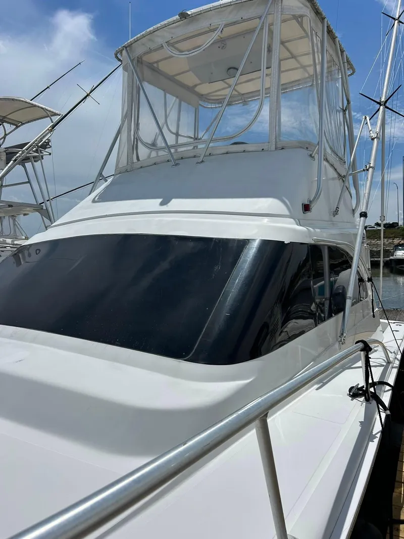 Slide: The Image of 1996 Luhrs 32 Convertible boat with flybridge, docked under a clear blue sky. - 5