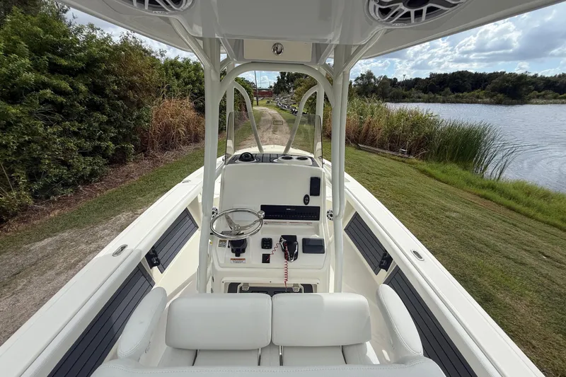 Slide: The Image of 2025 Pathfinder 2400 TRS boat interior with steering console, near a scenic lake. - 15