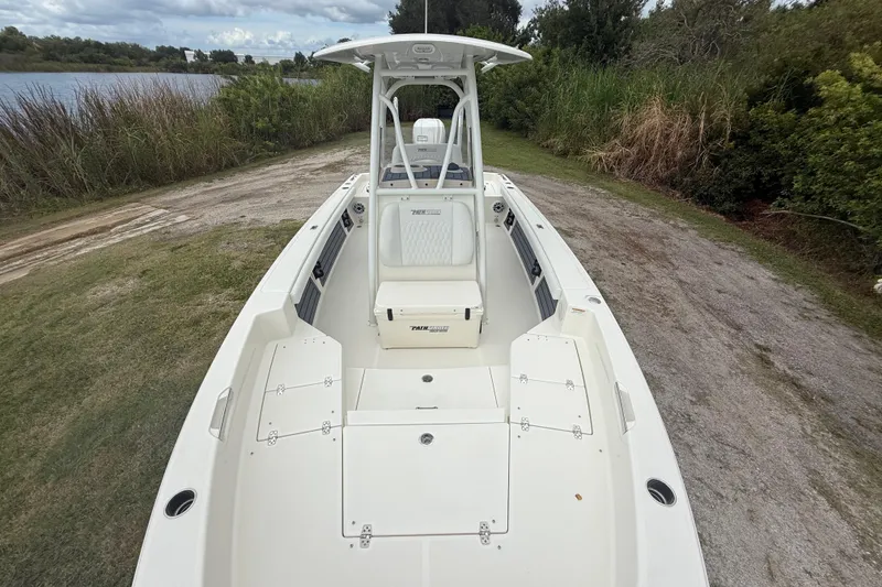 Slide: The Image of 2025 Pathfinder 2400 TRS boat on grassy shore, near a lake and lush greenery. - 20