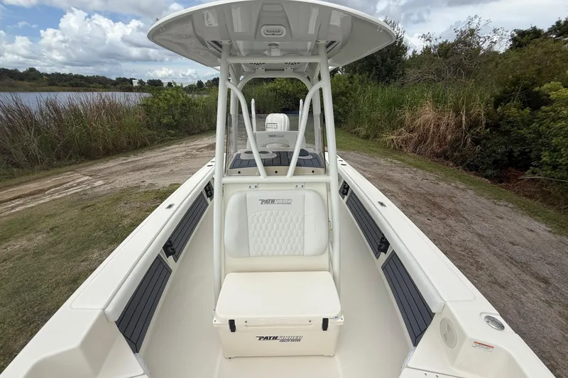 Slide: The Image of 2025 Pathfinder 2400 TRS boat with seating, docked near a grassy shoreline under cloudy skies. - 21