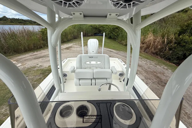 Slide: The Image of 2025 Pathfinder 2400 TRS boat interior with seating and console, near a lake. - 22