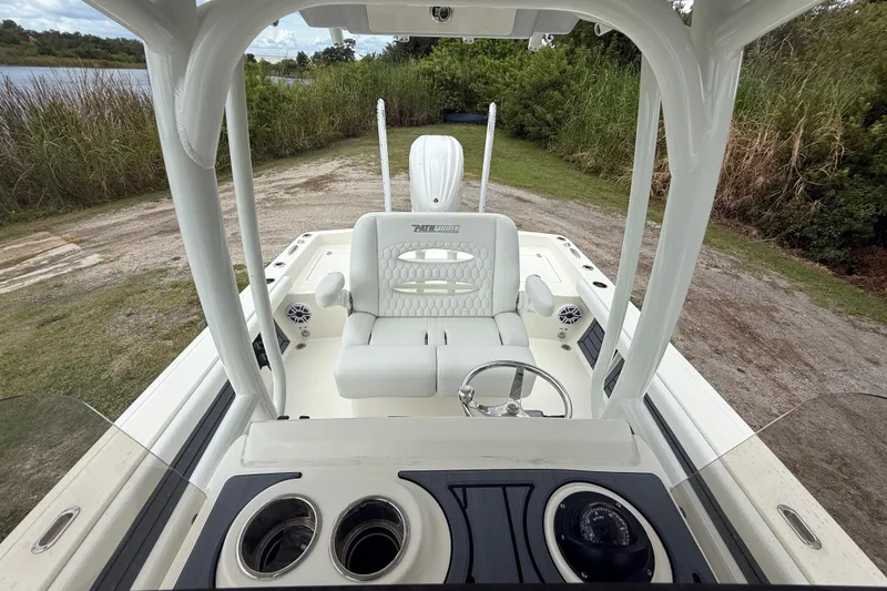 Slide: The Image of 2025 Pathfinder 2400 TRS boat interior with steering wheel and seating, docked near lush greenery. - 23