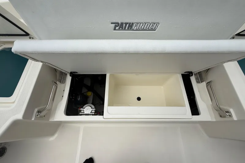 Slide: The Image of 2025 Pathfinder 2400 TRS boat storage compartment with open lid, showcasing interior features. - 28