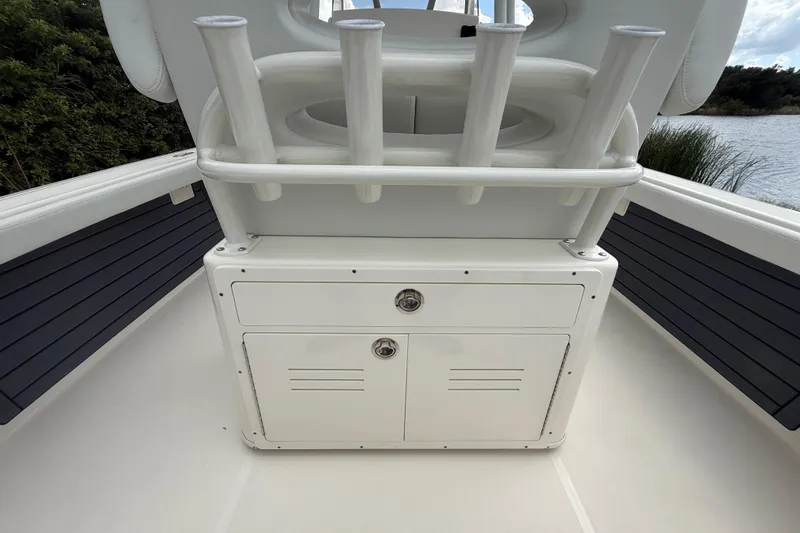 Slide: The Image of 2025 Pathfinder 2400 TRS boat storage compartment with rod holders, near water. - 30
