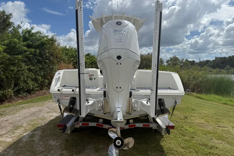Slide: The Image of 2025 Pathfinder 2400 TRS boat on trailer, rear view, outdoors with cloudy sky. - 4