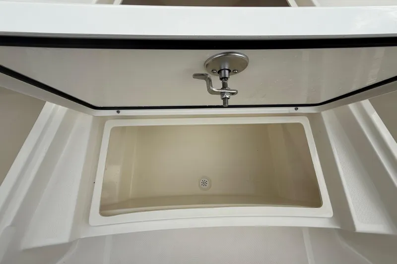 Slide: The Image of 2025 Pathfinder 2400 TRS boat storage compartment with open hatch and drainage. - 49