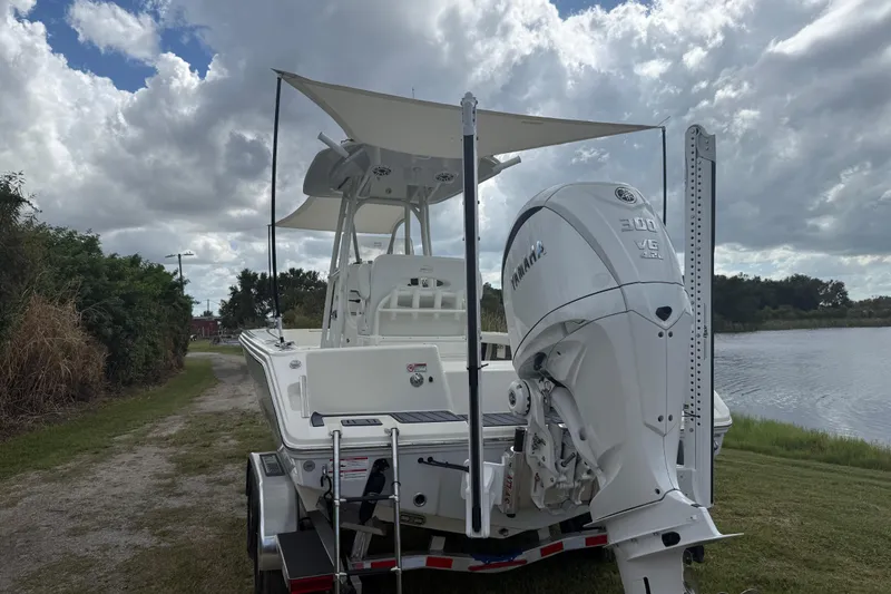 Slide: The Image of 2025 Pathfinder 2400 TRS boat with Yamaha engine, parked near a lake under cloudy skies. - 54