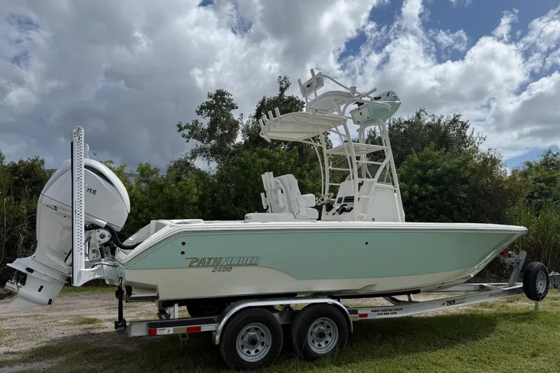 Slide: The Image of 2025 Pathfinder 2400 Open boat on trailer, parked outdoors under cloudy sky. - 2