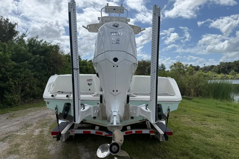 Slide: The Image of 2025 Pathfinder 2400 Open boat with powerful outboard motor, parked on a trailer by a lake. - 3