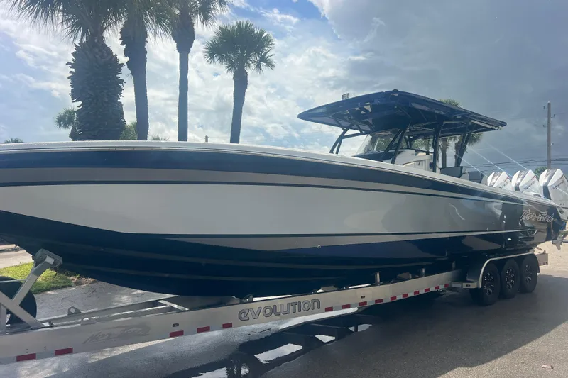 Slide: The Image of 2026 Nor-Tech 390 Sport Center Console boat on trailer, parked under palm trees. - 15