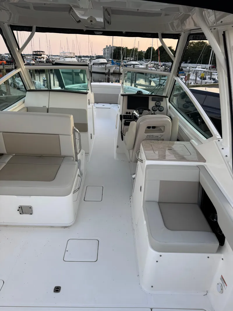 Slide: The Image of 2022 Boston Whaler 280 Vantage interior with seating and helm, docked at marina. - 17