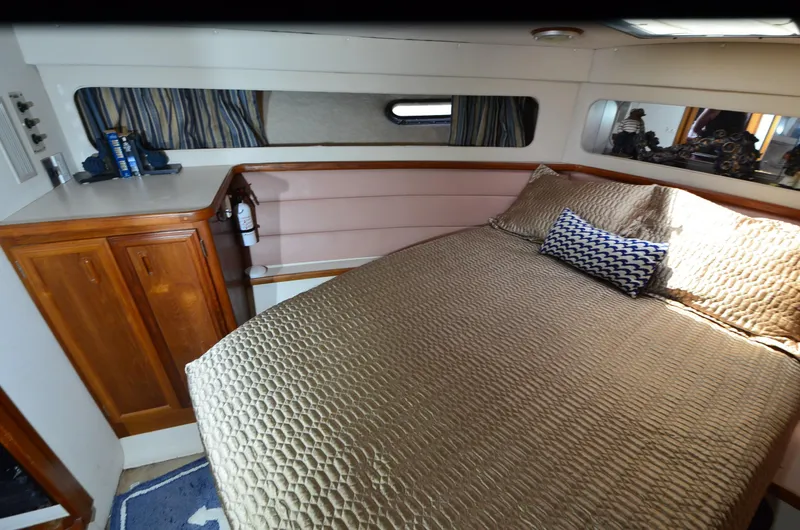 Slide: The Image of 1989 Carver Santego 3867 cabin interior with bed, wooden cabinets, and nautical decor. - 19