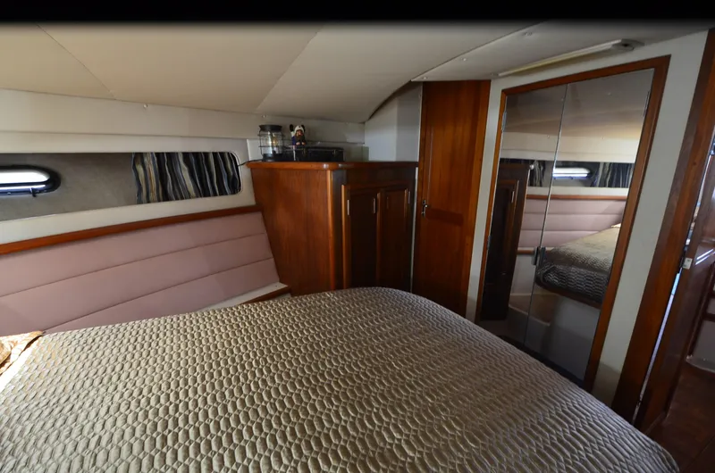 Slide: The Image of 1989 Carver Santego 3867 yacht interior with bed, wood cabinets, and mirrored closet. - 20