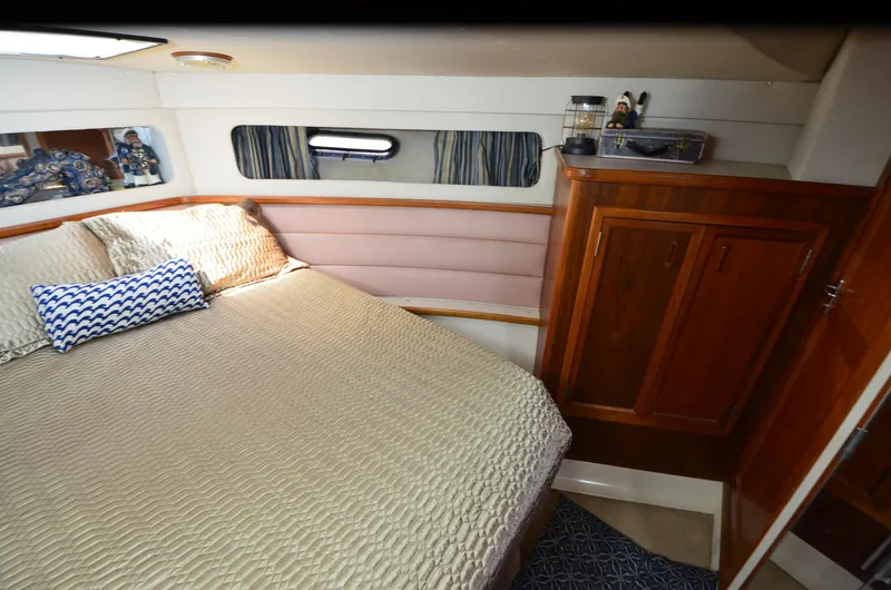 Slide: The Image of 1989 Carver Santego 3867 cabin interior with bed, wooden cabinets, and nautical decor. - 24