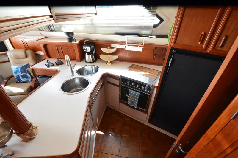 Slide: The Image of 1989 Carver Santego 3867 yacht kitchen with dual sinks, stove, and wooden cabinetry. - 29