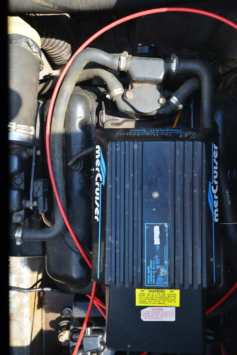 Slide: The Image of Engine of 1989 Carver Santego 3867 with MerCruiser components, featuring hoses and warning labels. - 36