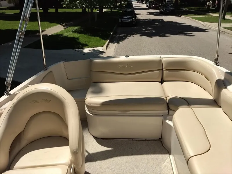 Slide: The Image of 2001 Sea Ray 190 Bow Rider boat interior with beige seating on a sunny street. - 7