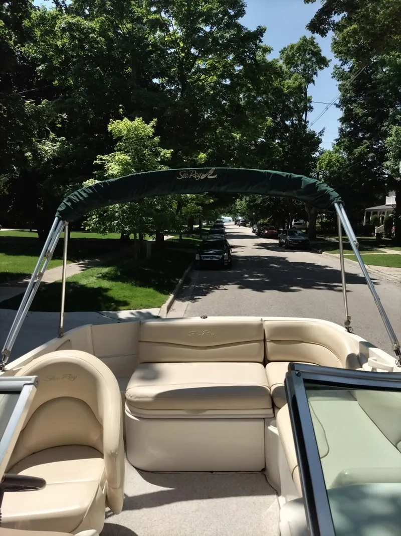 Slide: The Image of 2001 Sea Ray 190 Bow Rider boat with beige seating and canopy on a sunny street. - 8