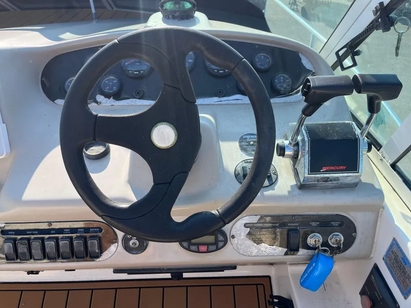 Slide: The Image of 2004 Cruisers Yachts 320 Express helm with steering wheel and Mercury throttle controls. - 15